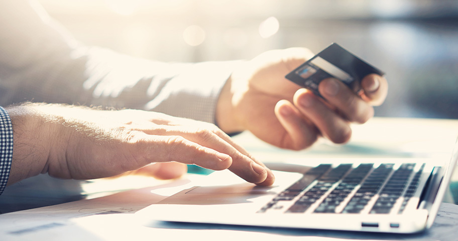 Person holding a debit card while shopping on their laptop.